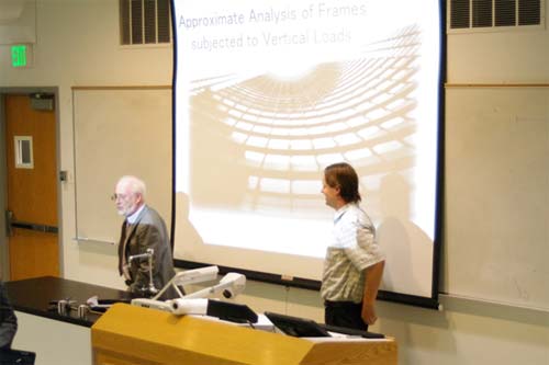Two men at the front of a classroom presenting their research