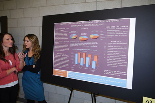Two females in conversation next to a research poster