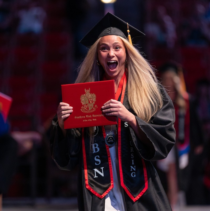 SUU graduates throwing caps in air during graduation ceremony.