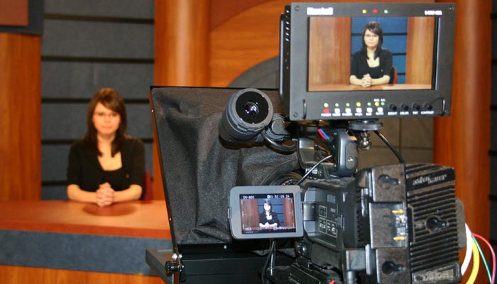 Image of TV camera and student on news set