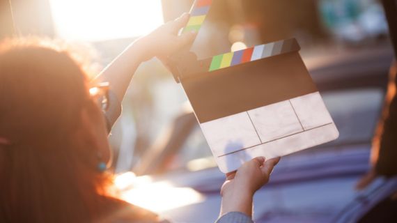 A woman holds a film clapboard. Image advertising the SUU Winter Screening.