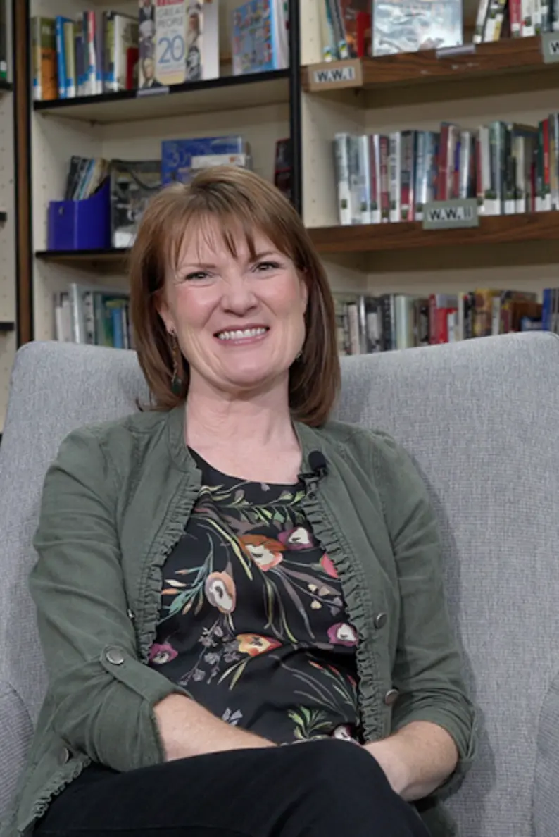 Mariah Wheeler sits in a comfortable chair in a library setting