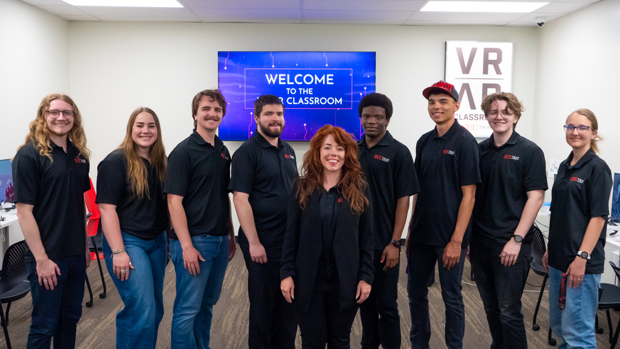 VR/AR Team in the VR/AR Classroom with the tv behind them saying "Welcome to the VR/AR Classroom".