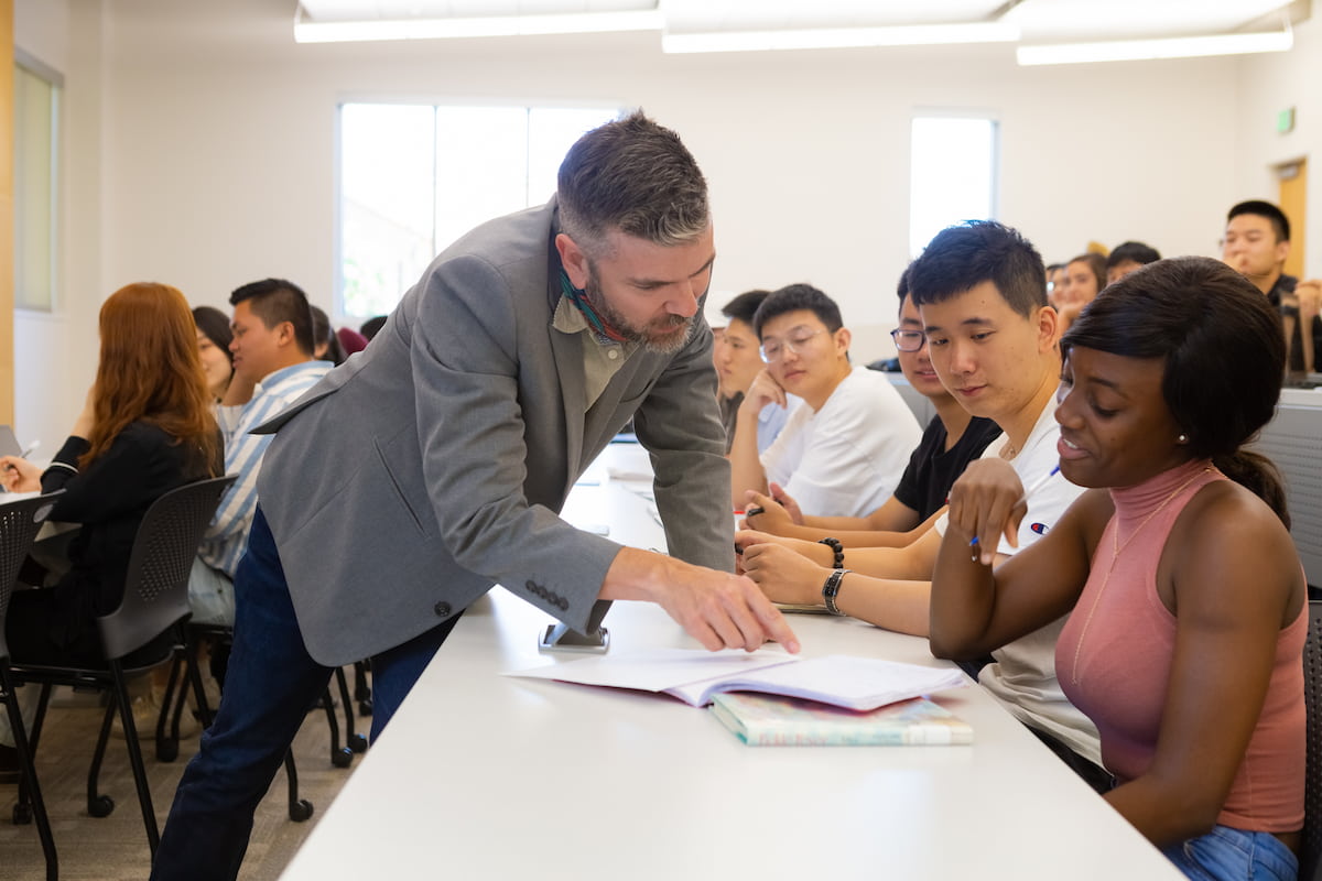 Southern Utah University English professor helping student in classroom assisting with coursework for bachelor degree program.