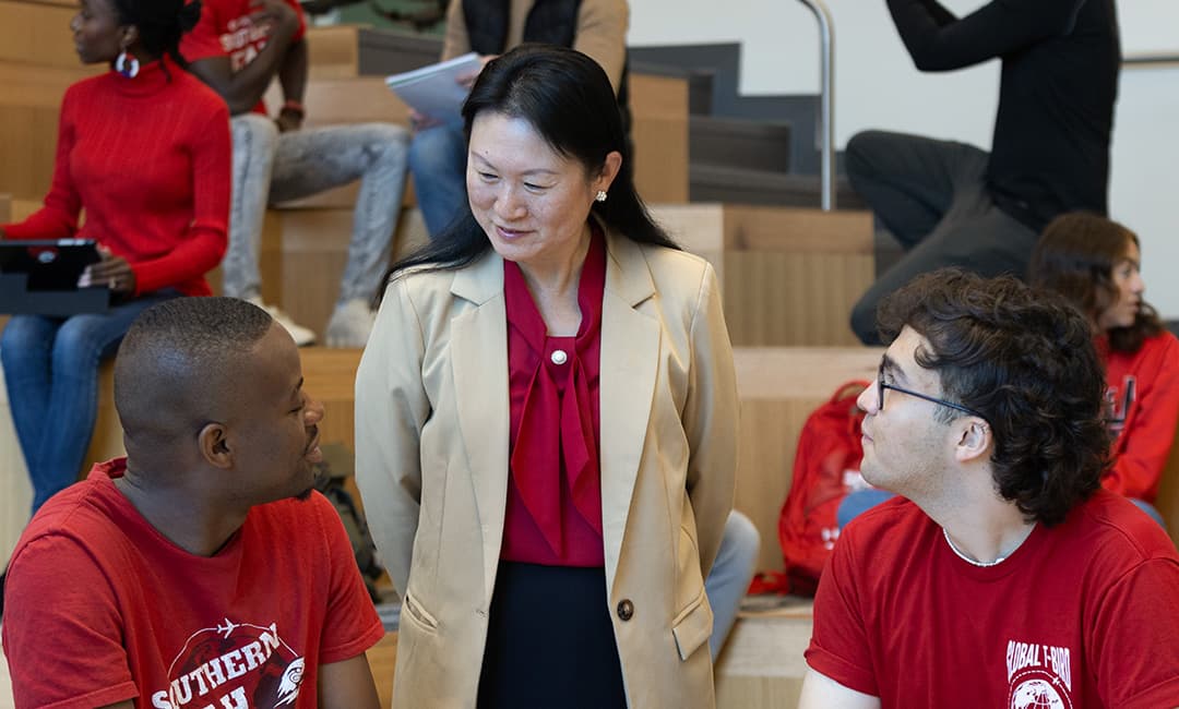 An SUU professor in a classroom standing between two SUU students with red shirts