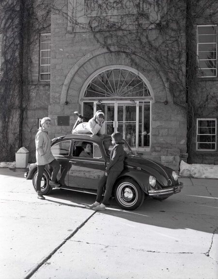 SUU students in 1960 posing with an old car in front of Old Maine