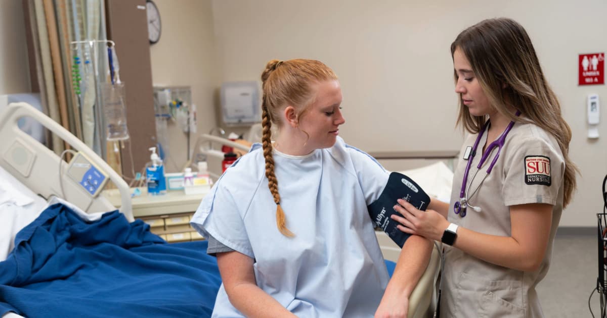 Nursing student with patient checking vitals.