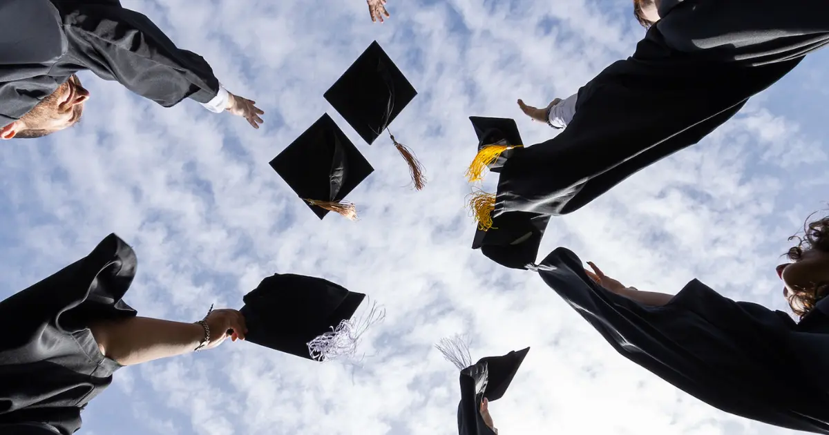 Students throw their graduation caps into the air.