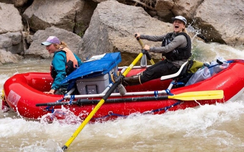 Two girls smiling in a big inflatable raft on the river