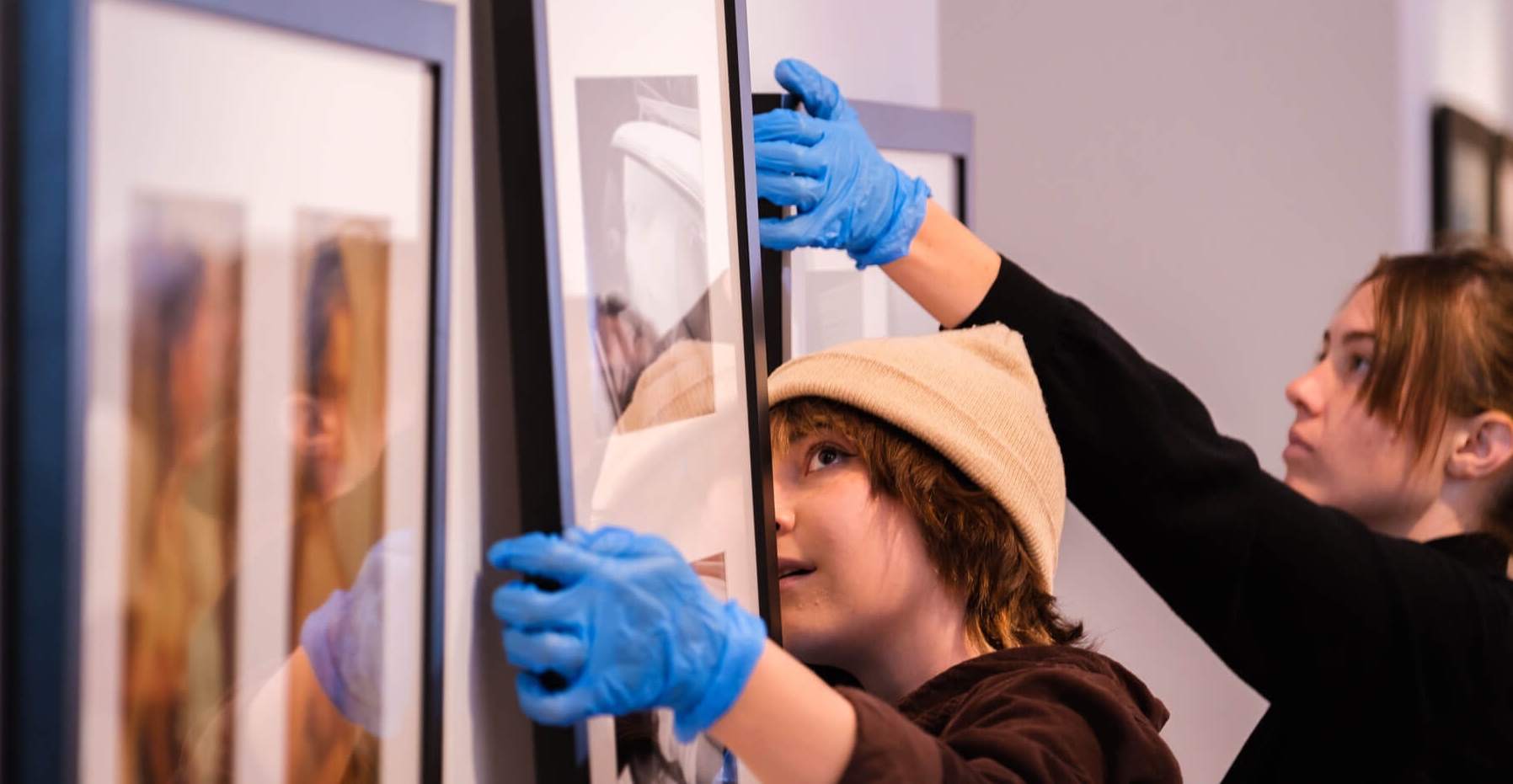 Workers install an exhibition by hanging pieces at SUMA.